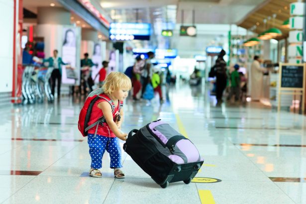 طفل صغير يحمل حقيبة سفر في مبنى مطار