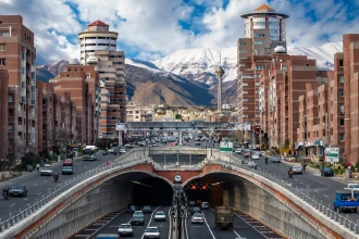 Verkehrsreiche Straße in Teheran mit Tunneln und schneebedecktem Alborzgebirge