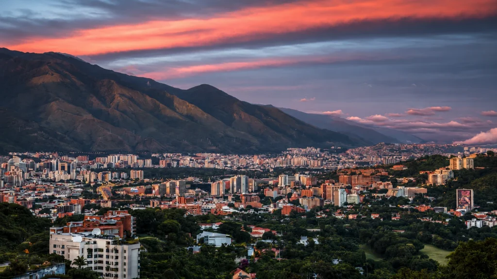 Caracas unter rötlichem Abendhimmel mit dicht bebauten Vierteln vor dem Ávila-Gebirge