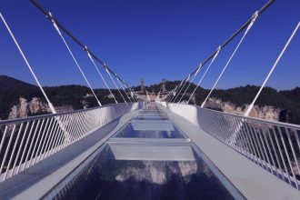Die Zhangjiajie Grand Canyon Glass Bridge hoch über einer bewaldeten Schlucht