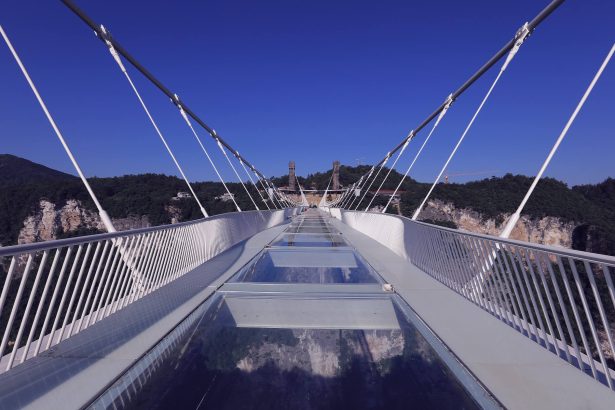 Die Zhangjiajie Grand Canyon Glass Bridge hoch über einer bewaldeten Schlucht
