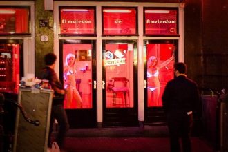 Kanal und rot beleuchtete Fenster in Amsterdams De Wallen