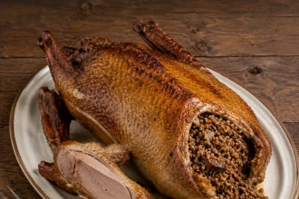 Ganso asado entero relleno de trigo sarraceno con una loncha de pechuga cortada en una fuente ovalada
