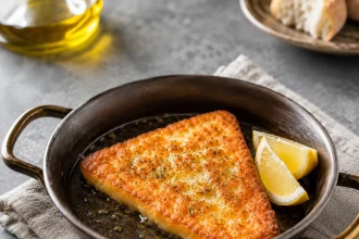 Tranche carrée de saganaki doré dans une petite poêle noire