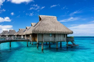 透明な海に建つ茅葺き屋根の水上バンガロー群