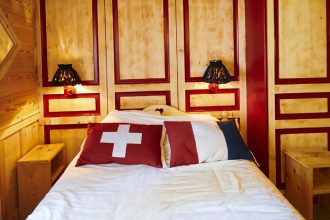フランスとスイスの国旗柄クッションが置かれたホテル・アルベの木張り客室