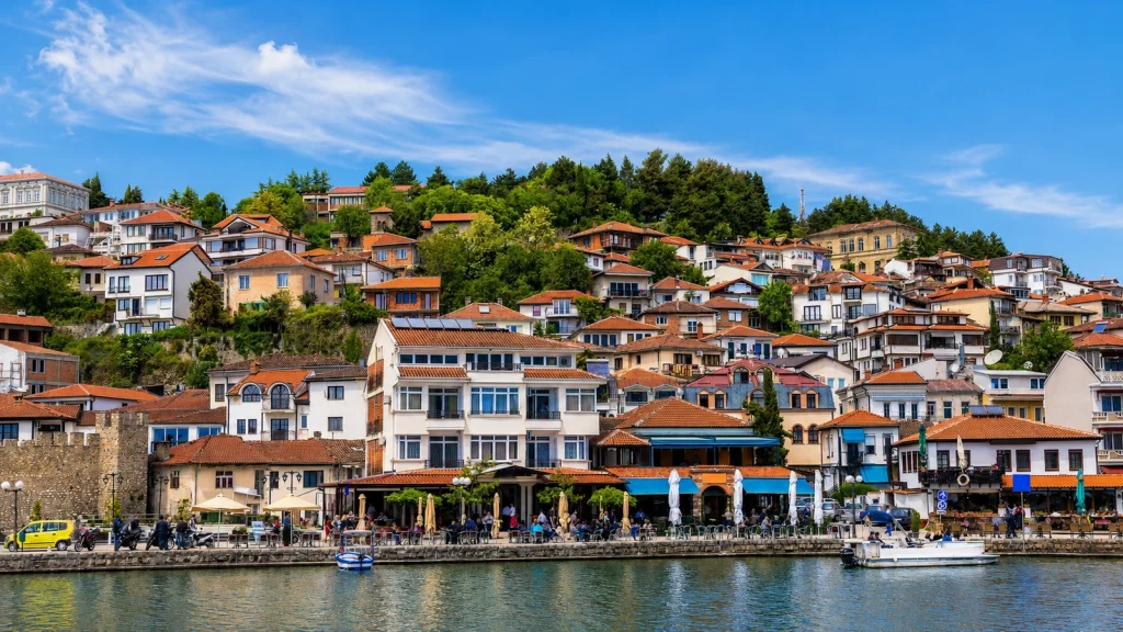 Witte huizen langs de waterkant van Ohrid onder groene heuvels