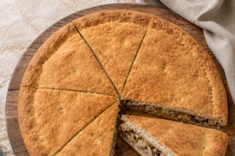 Vierkante bovenaanzicht van een ronde Viška pogača met uitgesneden punt en zichtbare lagen brood
