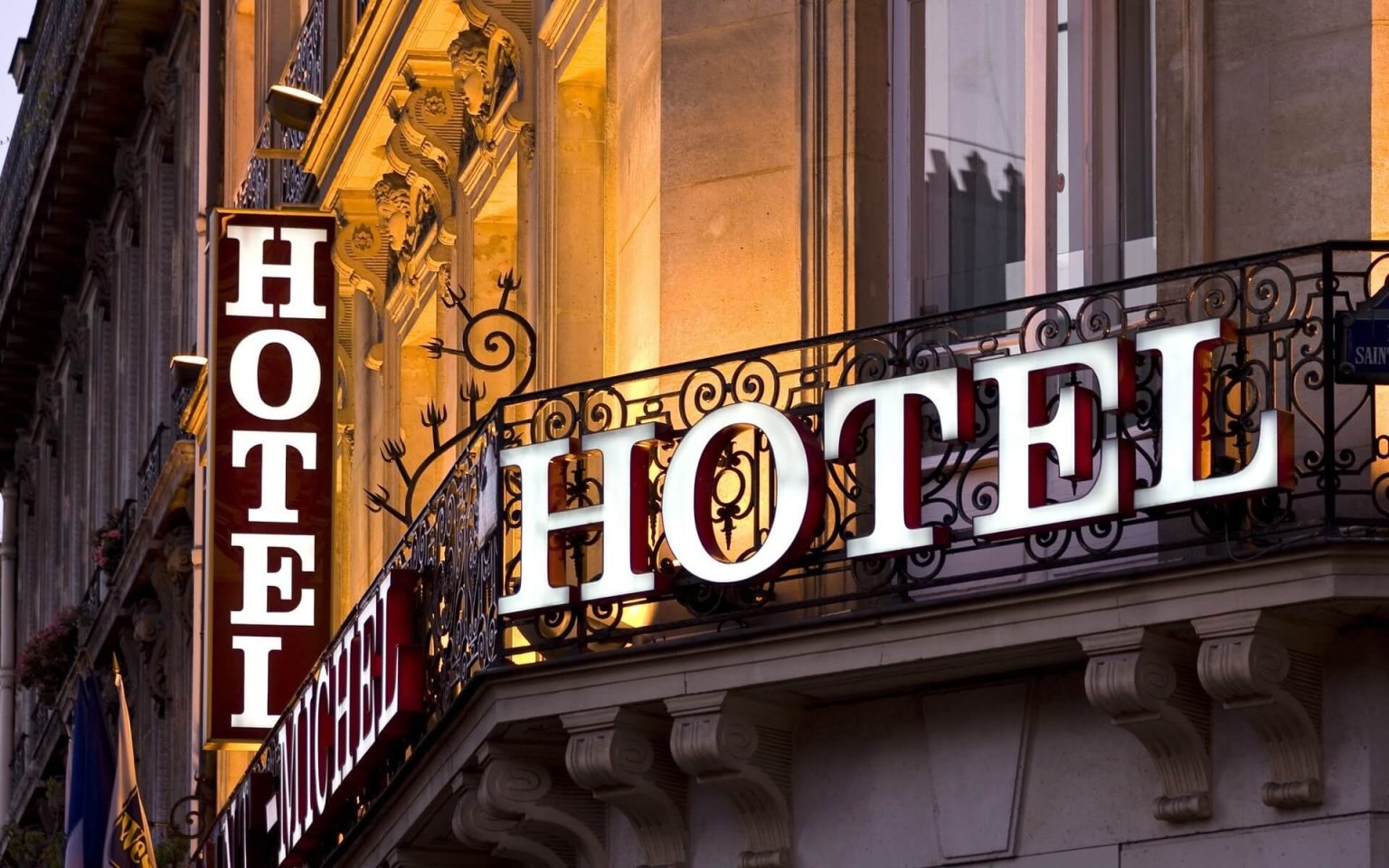 Verlichte hotelborden met sterren aan de gevel van een stadshotel