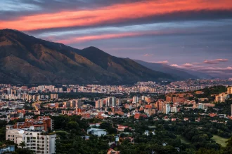 Каракас заполняет горную долину под красно-синим небом после заката