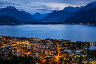 Osvetljeni grad na obali alpskog jezera u Švajcarskoj