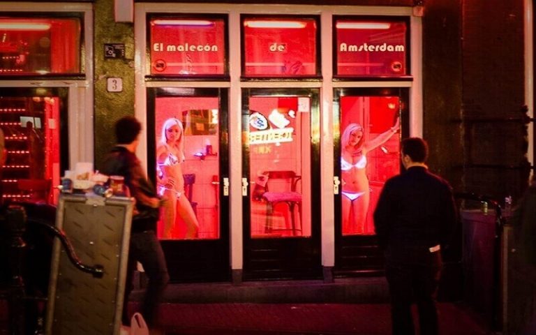 Zgrade uz kanal i crveno osvetljeni izlozi noću u amsterdamskom De Valenu
