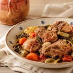 Square photograph of rustic lamb stew in a shallow bowl with visible potato chunks