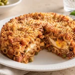 Square photograph of a tall slice of baked anelletti with visible ring pasta